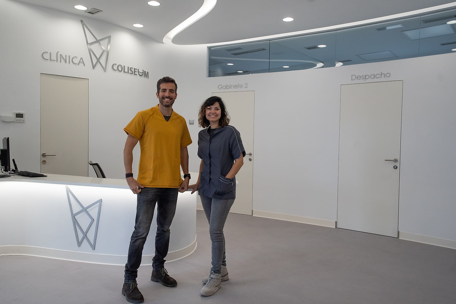Recepción de Clínica Coliseum en Segovia, con el logotipo de la clínica en la pared y dos profesionales del equipo junto al mostrador